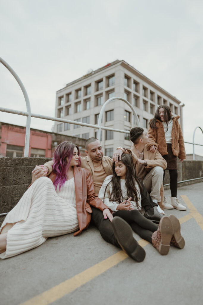 A family portrait of a male and female sitting in field on cement parking garage with children near Pioneer Square, Seattle, WA