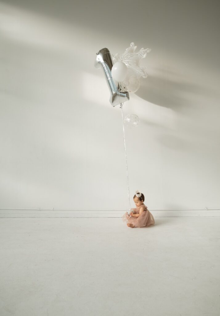 A newborn portrait of a baby wearing pink tutu dress holding silver balloon at Northlight Studio near Seattle, WA