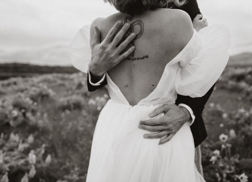 A closeup of a bride and groom embracing in field at Rowena Crest Viewpoint.