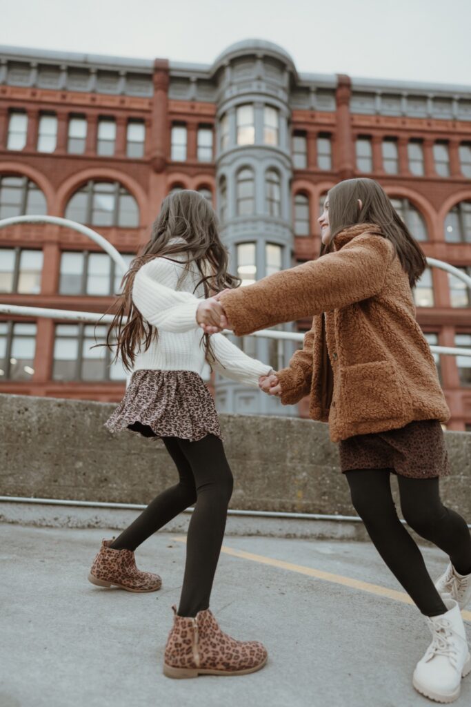 A portrait of two girls playing ring around the rosy in Pioneer Square