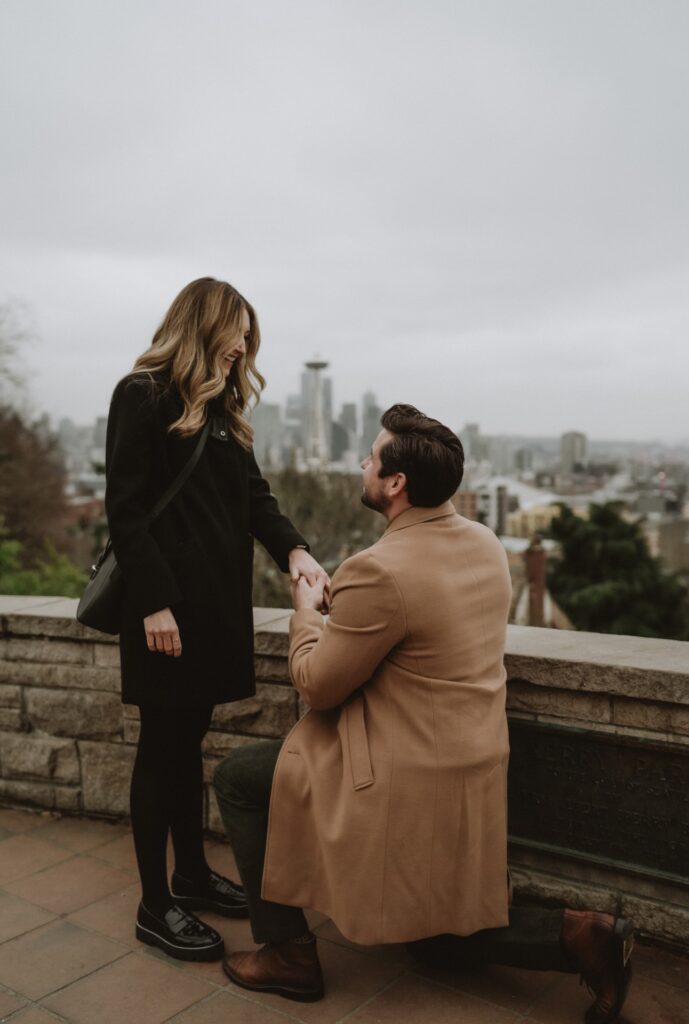 A couples portrait of a male on one knee proposing to female at Kerry Park near Seattle, WA