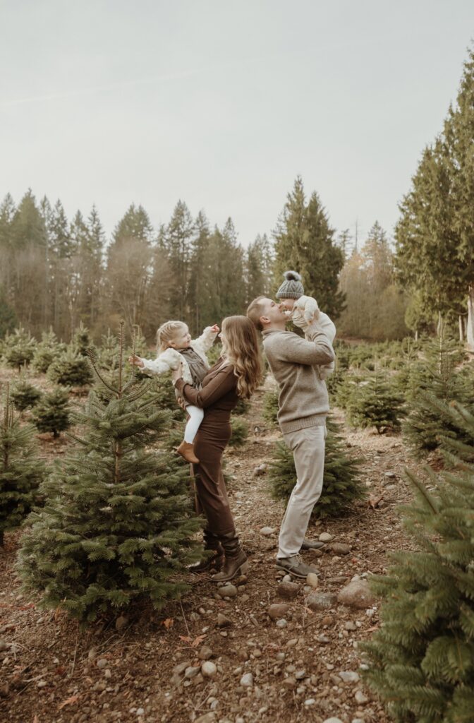 A family portrait of a male and female playing with children at Christmas tree farm near Issaquah, WA