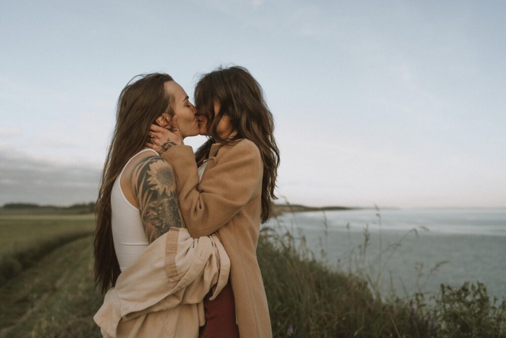 A couples portrait of a two females kissing in field at Ebey's Landing near Whidbey Island, WA