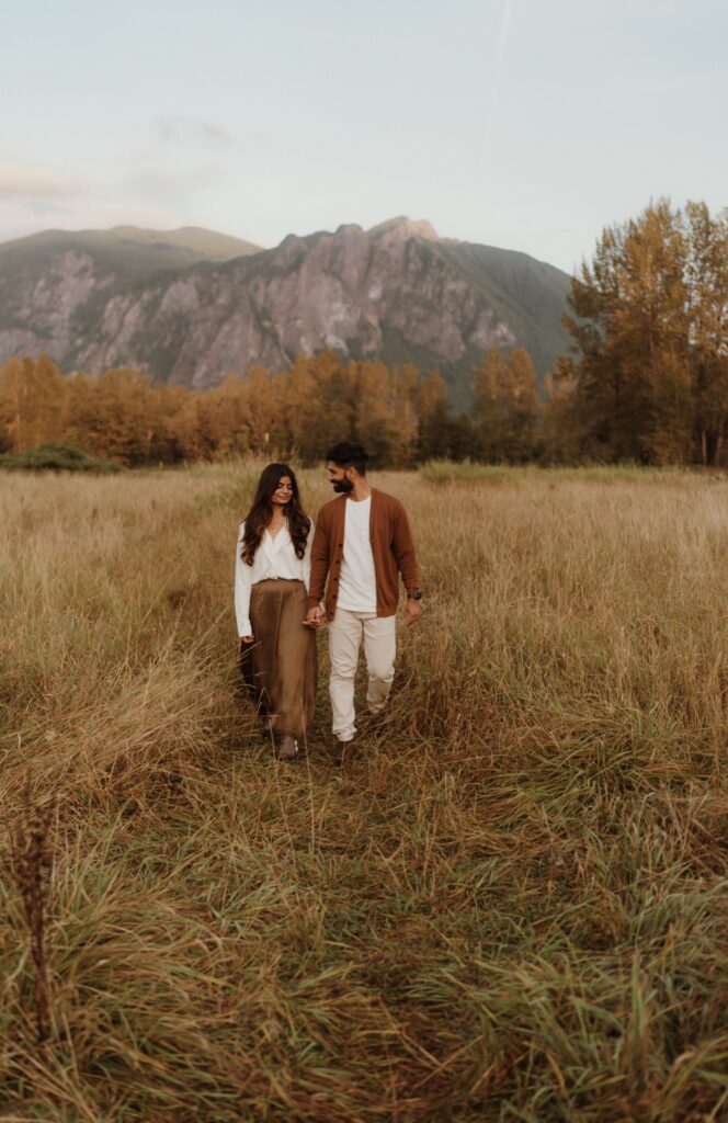 A couples portrait of a male and female walking in field at Mount Si near North Bend, WA