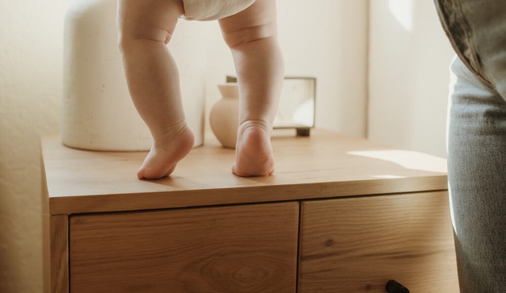 A baby closeup photo of a baby standing on dresser