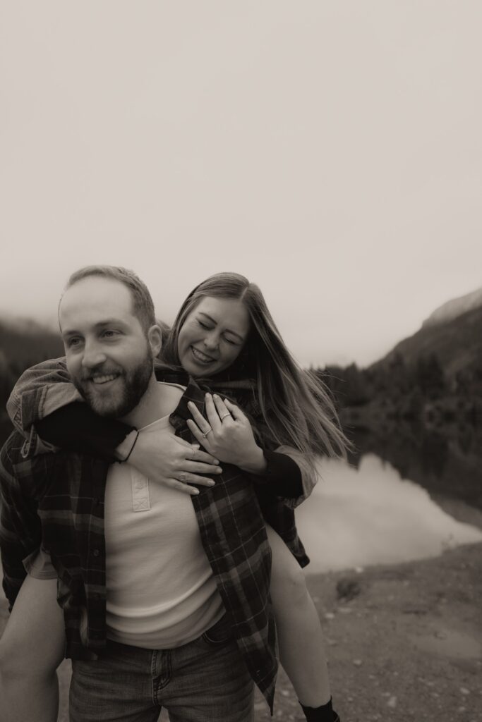 A couples black and white portait of a male and female doing piggyback ride at Gold Creek Pond near Snoqualmie Pass, WA