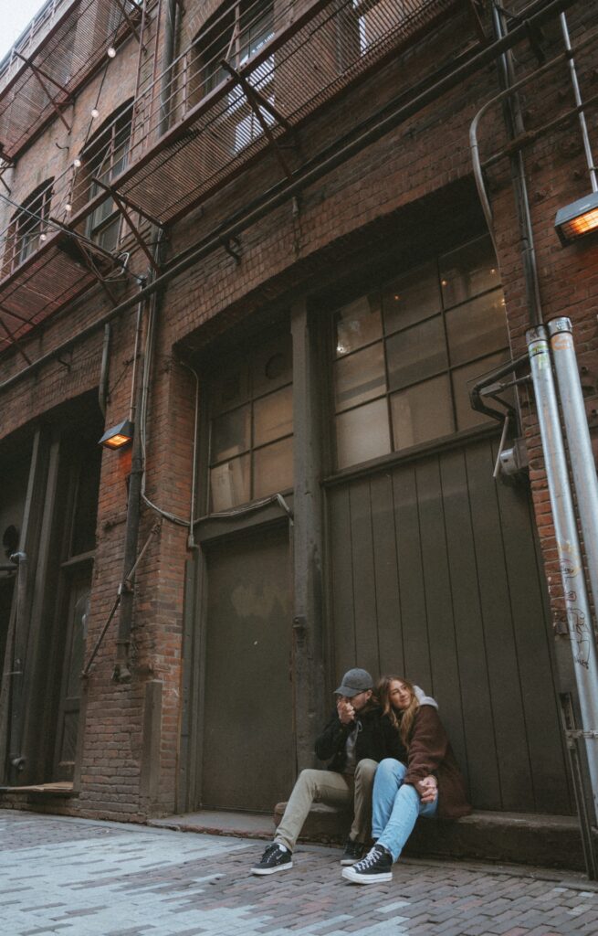 A portrait of a male and a female couple sitting on alleyway stoop near Pioneer Square, Seattle.