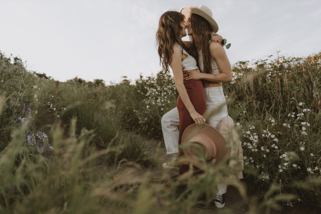 A couples portrait of two females wearing tank tops embracing in wildflower field at Ebey's Landing near Whidbey Island, WA
