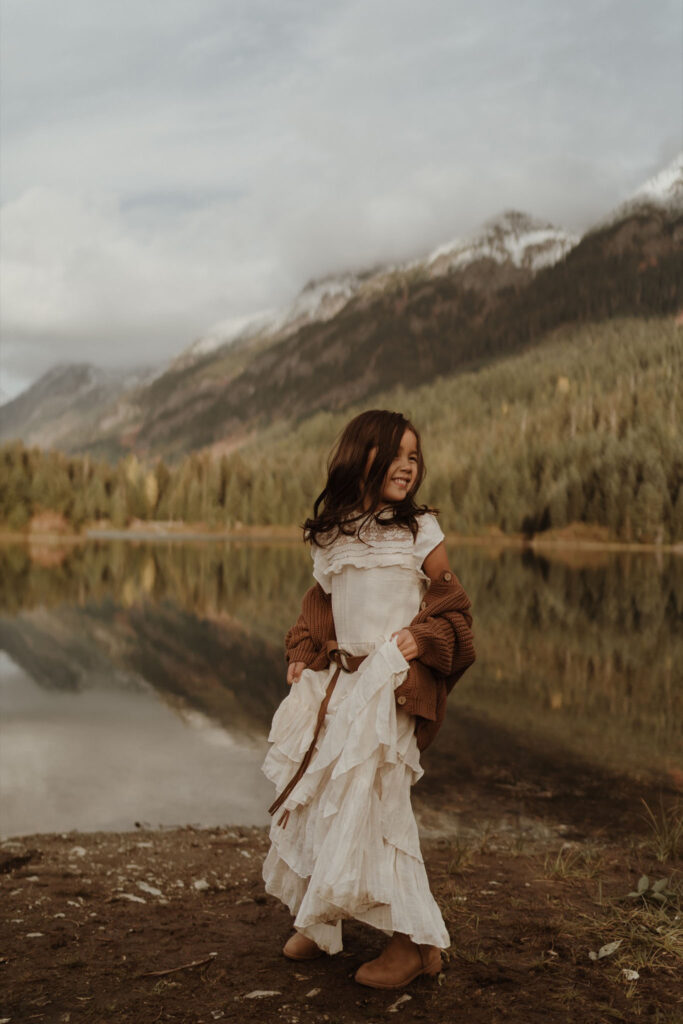 A children's portrait of a little girl wearing white dress playing with skirt at Gold Creek Pond near Snoqualmie Pass, Seattle, WA.