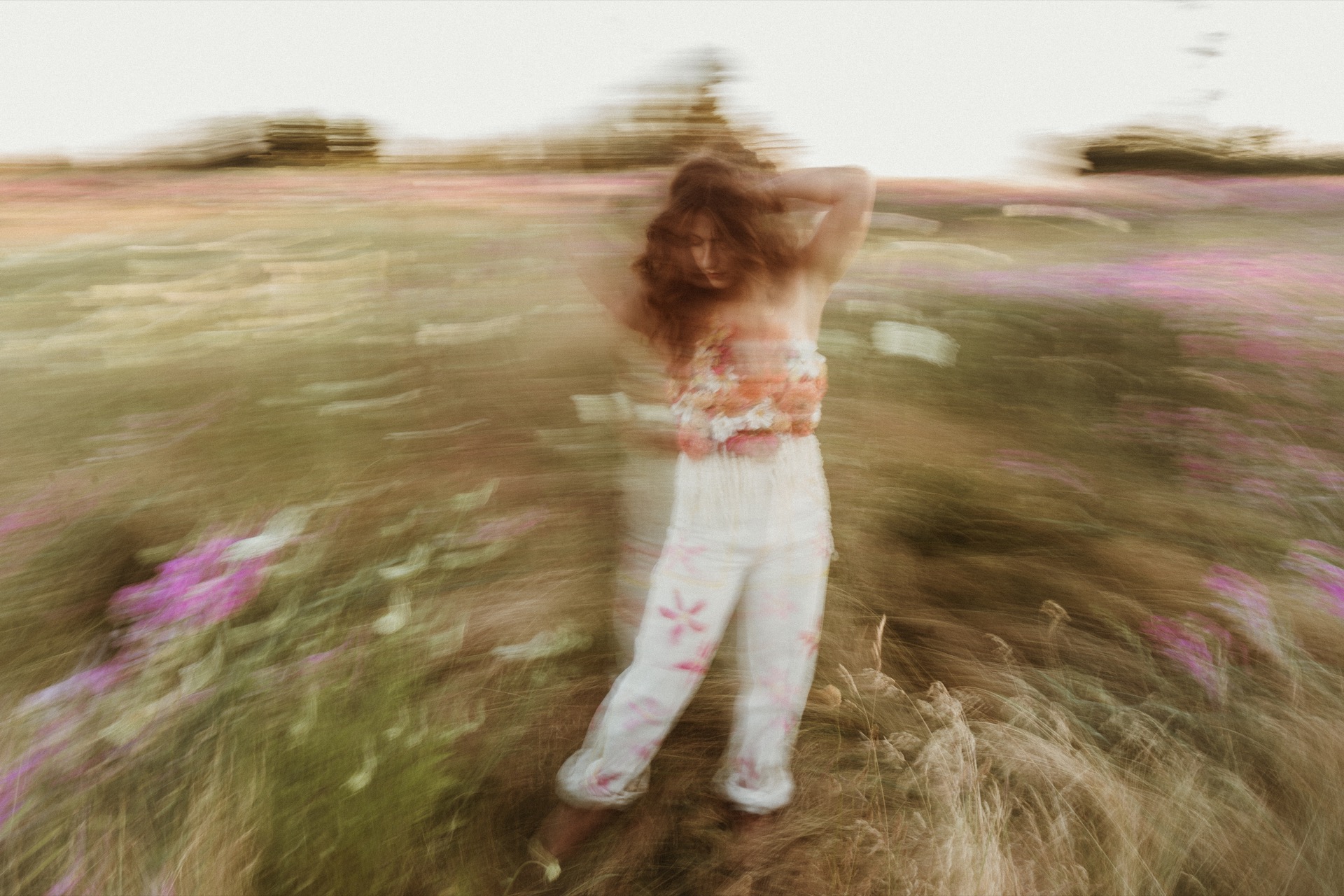 A portrait of a female wearing floral top spinning in field at Discovery Park near Seattle, WA.