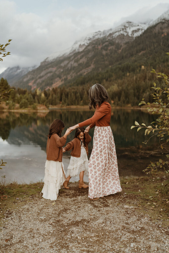 A family portrait of a female wearing long skirt playing ring around the rosy with little girls at Gold Creek Pond near Snoqualmie Pass, Seattle, WA.