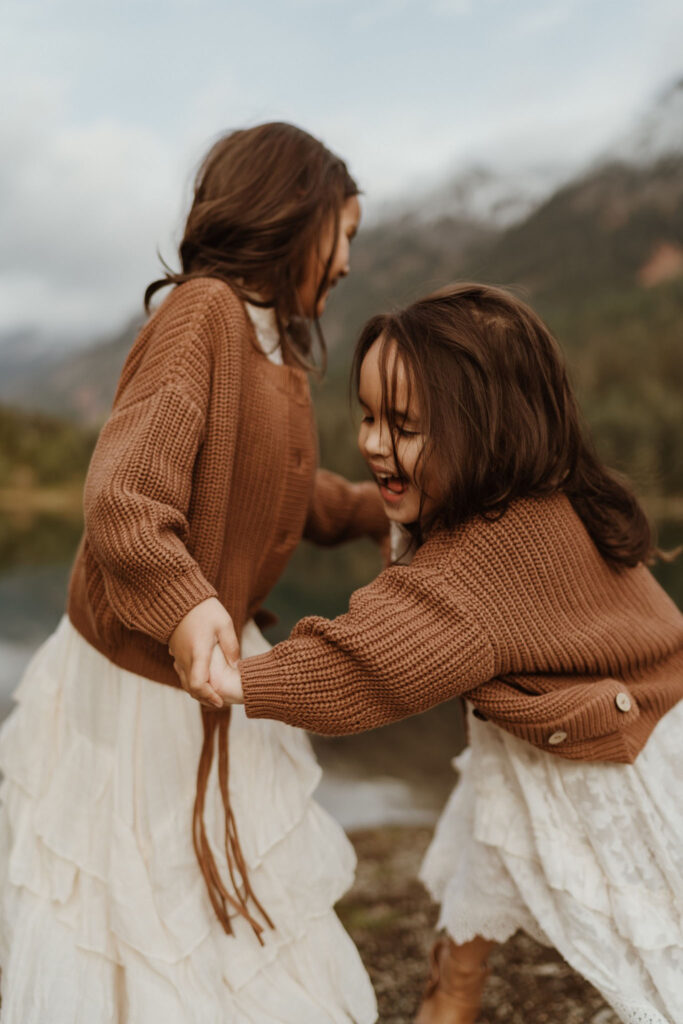 A children's portrait of two little girls wearing brown sweaters playing at Gold Creek Pond near Snoqualmie Pass, Seattle, WA.