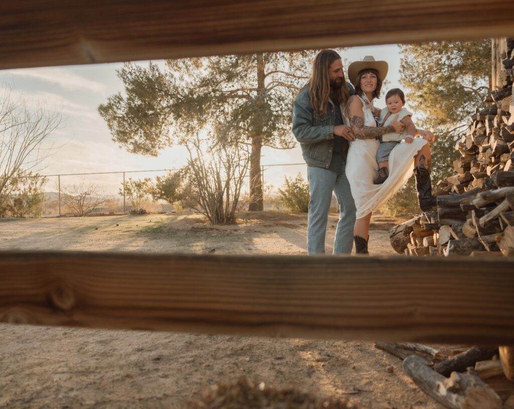 A family portrait of a male and female in western gear holding baby boy at ranch house near Yucca Valley, CA.