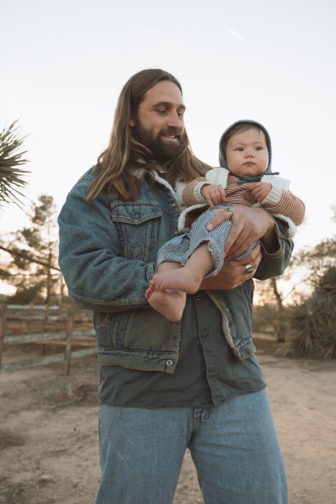 A portrait of a male with long hair holding baby boy near Joshua Tree, CA.