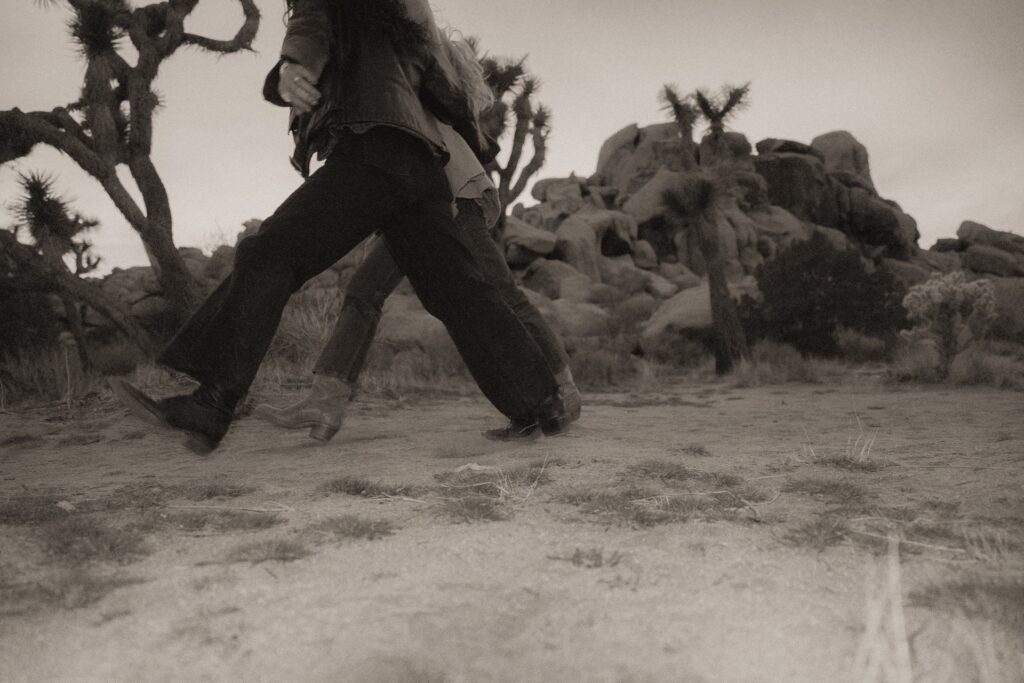 Two females walking in large strides in Joshua Tree National Park.