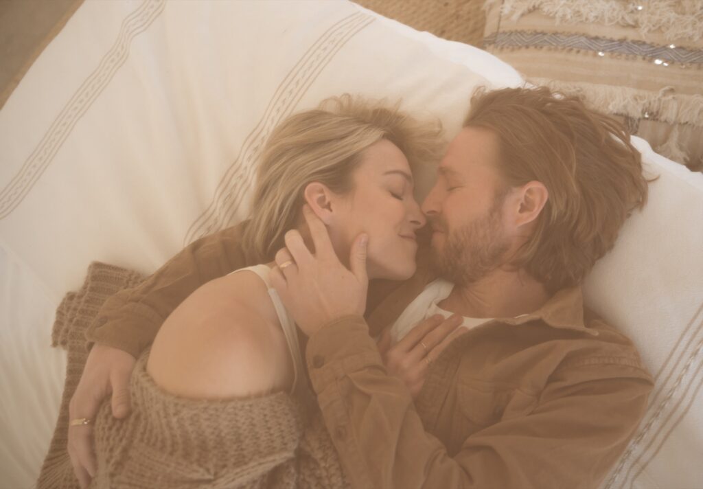 An overhead portrait of a male and female embracing on bed at home near Joshua Tree, California.