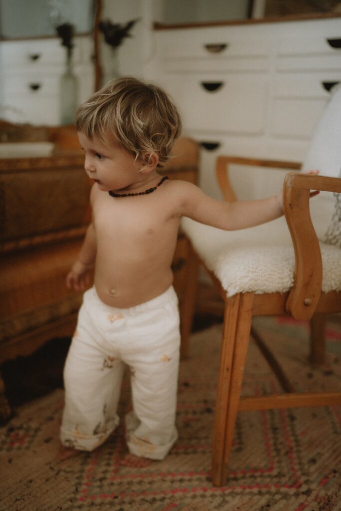 A portrait of a baby wearing white pants at home in Yucca Valley, California.
