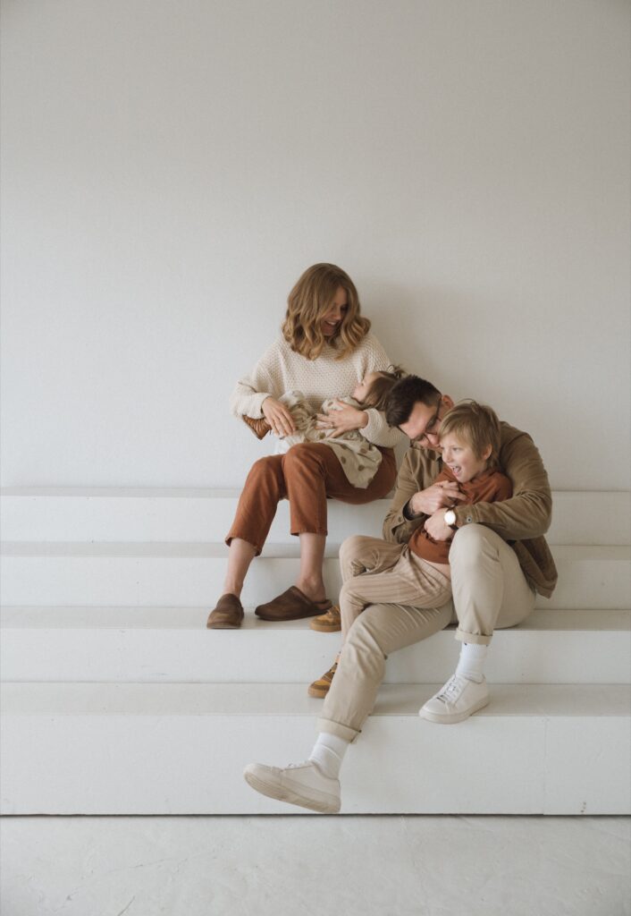 A family photo of a male and female sitting on white stairs with their kids in studio near Seattle, WA.