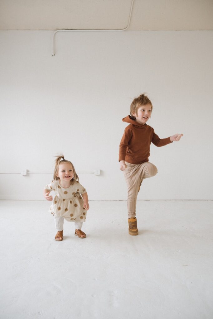 A portrait of two kids playing in all white studio near Seattle, WA.