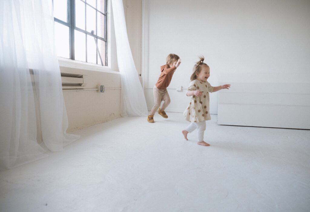 A portrait of a two kids running from white curtain in studio near Seattle, WA.