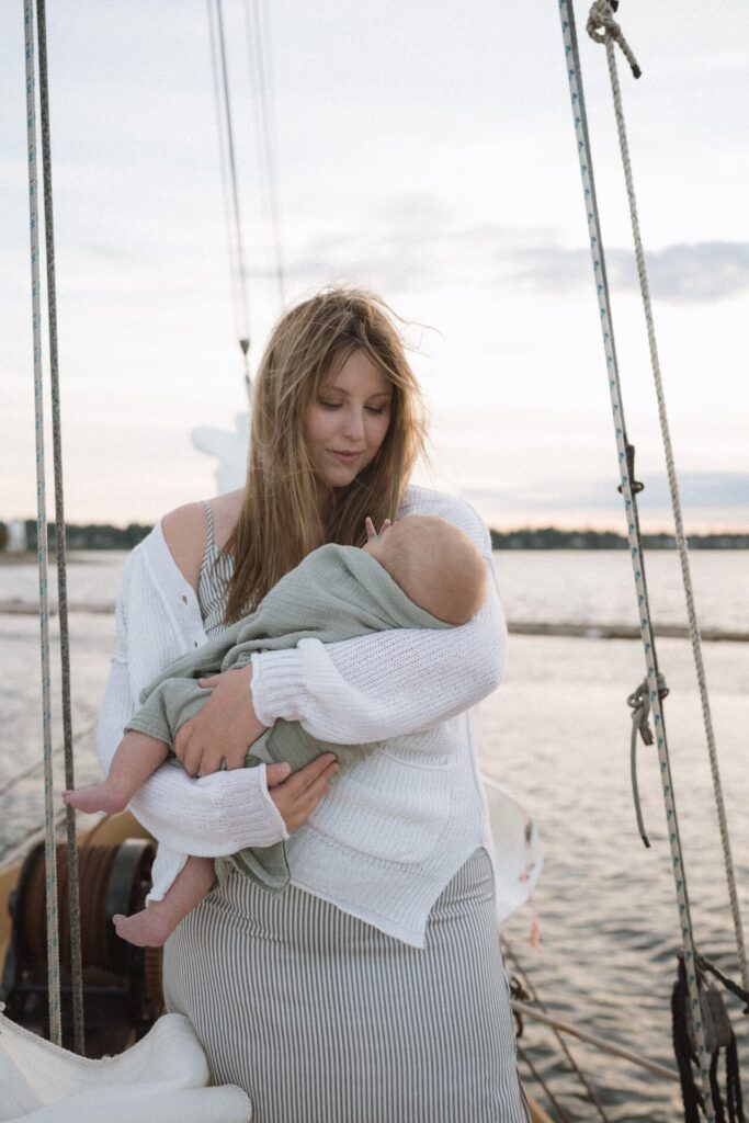 Mother holding newborn baby on sailboat