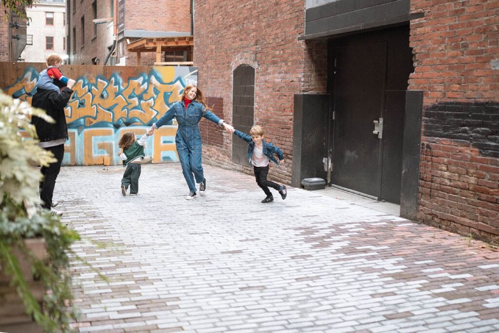 female playing with two boys in pioneer square alley