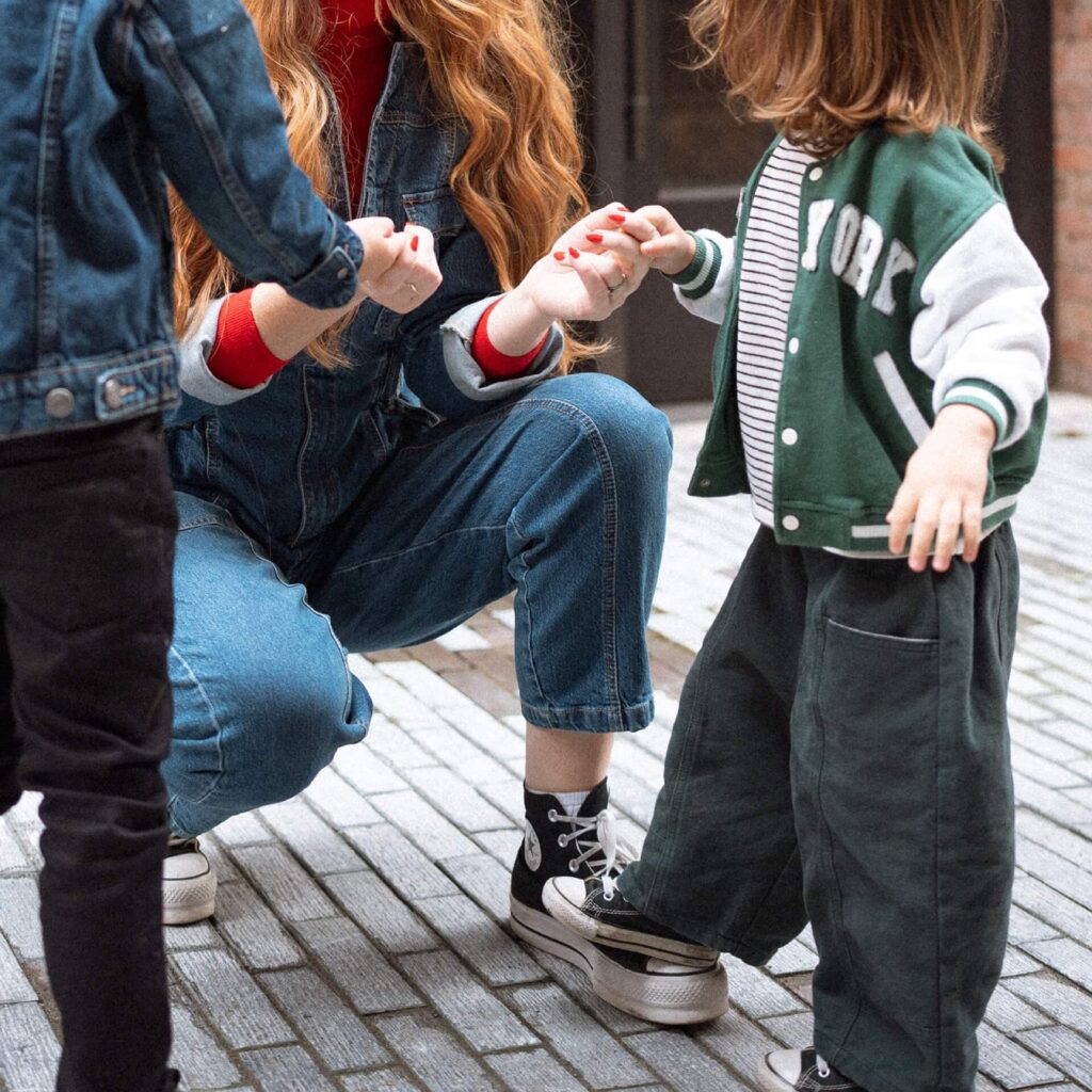 female holding two little boys hands in seattle alleyway