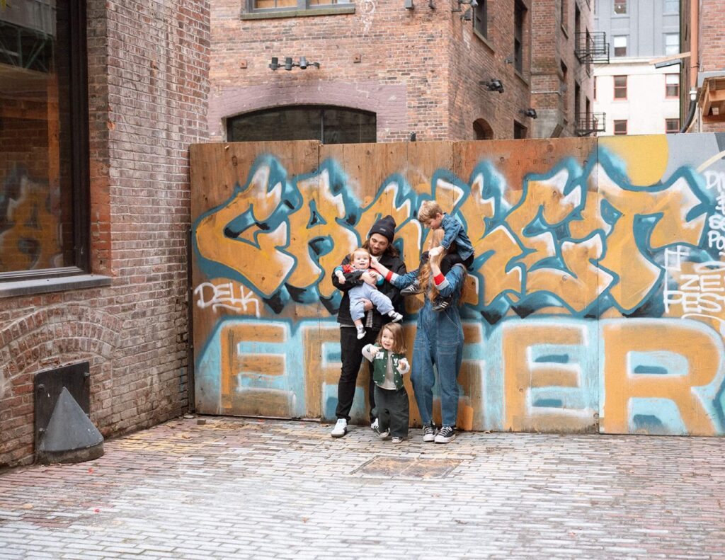 family of five standing against graffiti wall in seattle alleyway