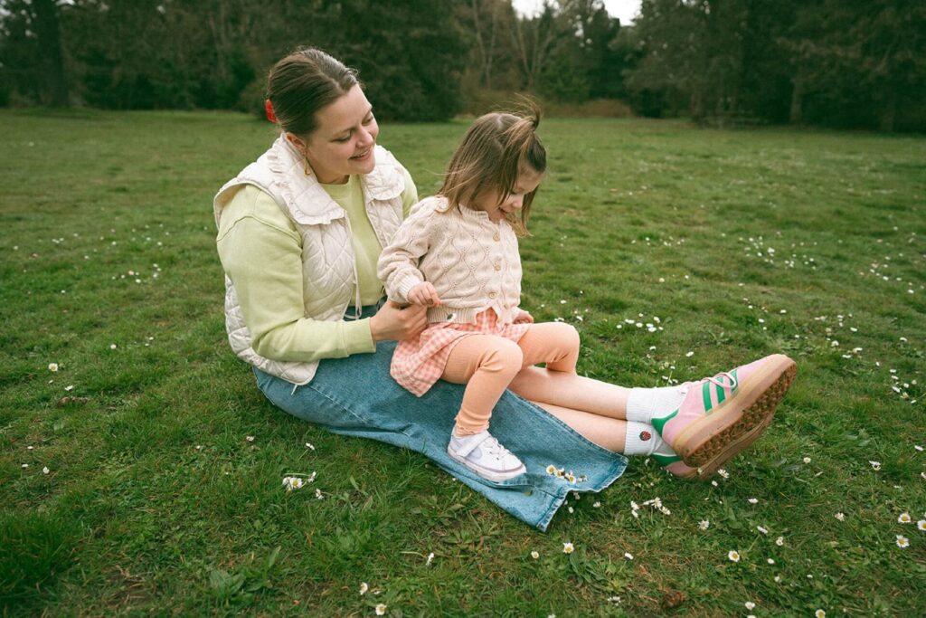 mother sitting with daughter on grassy field