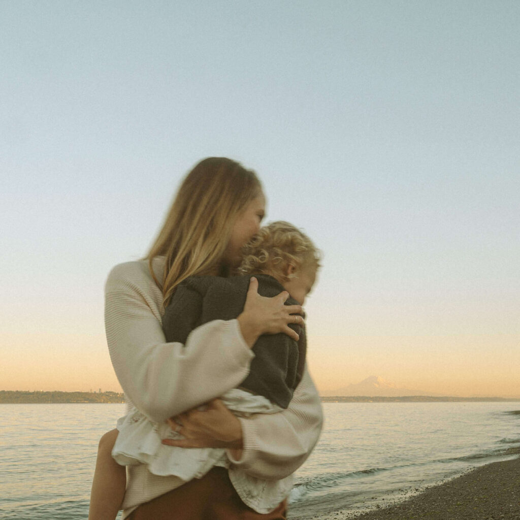 mother holding baby girl on beach bainbridge island