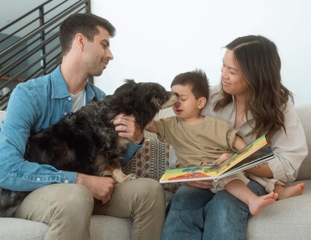 dog licking toddlers nose while reading