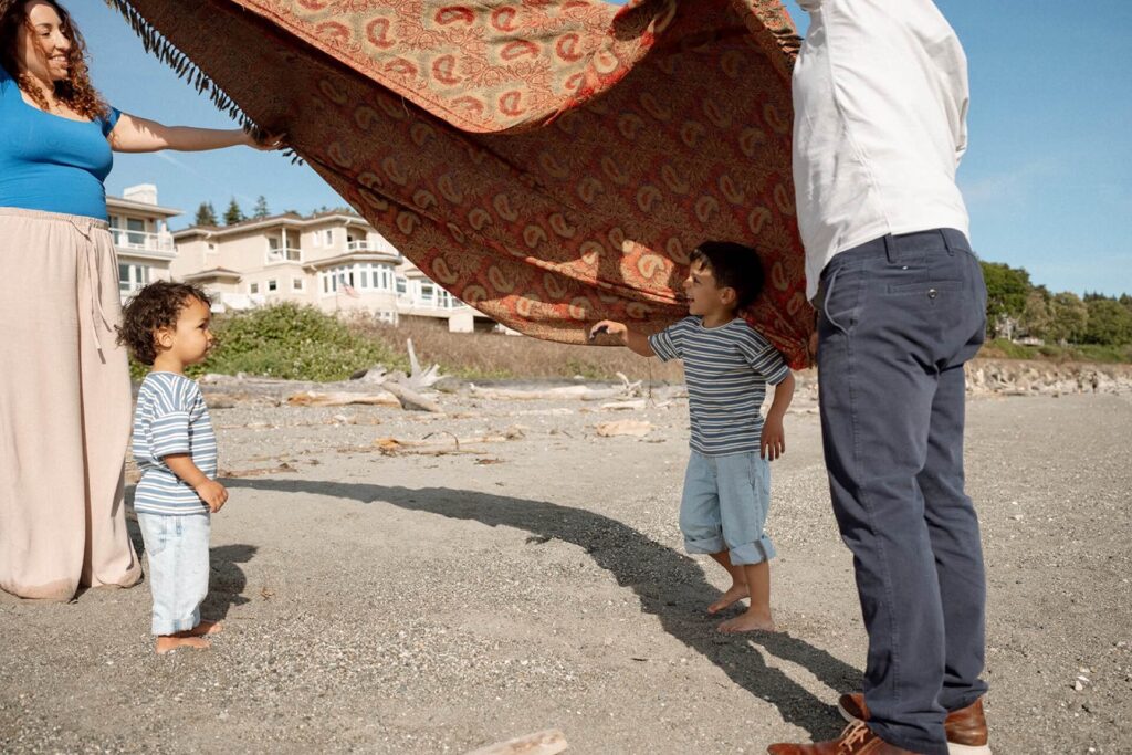 family playing with blanket and kids at beach in seattle