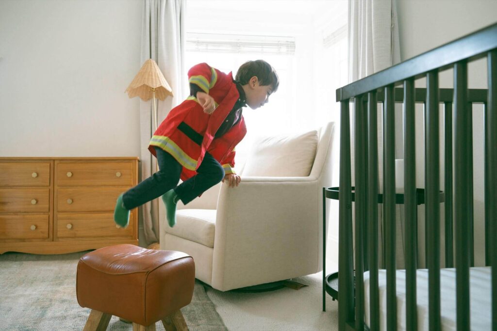 little boy hopping over chair at home