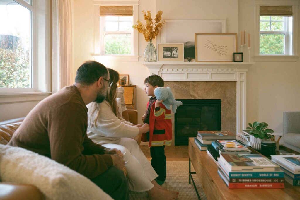 parents buttoning child costume at home