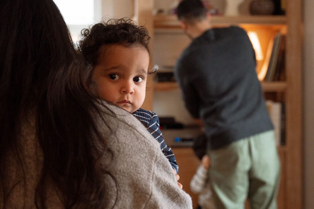 baby peeking at camera in mother's arms