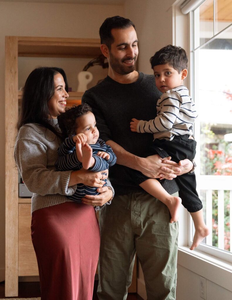 male and female holding two small kids at home