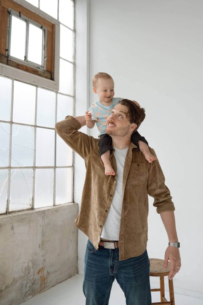 father holding baby boy on shoulder in studio