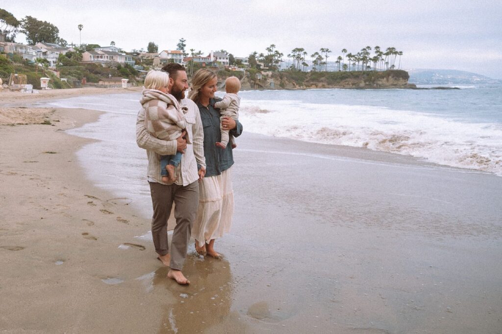 family wearing neutrals creams and blues walking at crescent bay beach