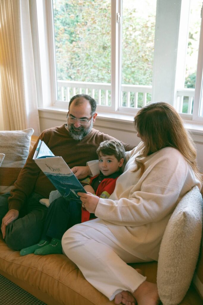 mother and father reading whale book to son on couch at home