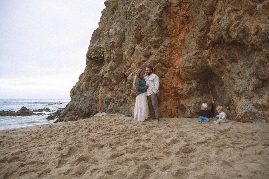 male and female hugging with two small children in sand crescent bay