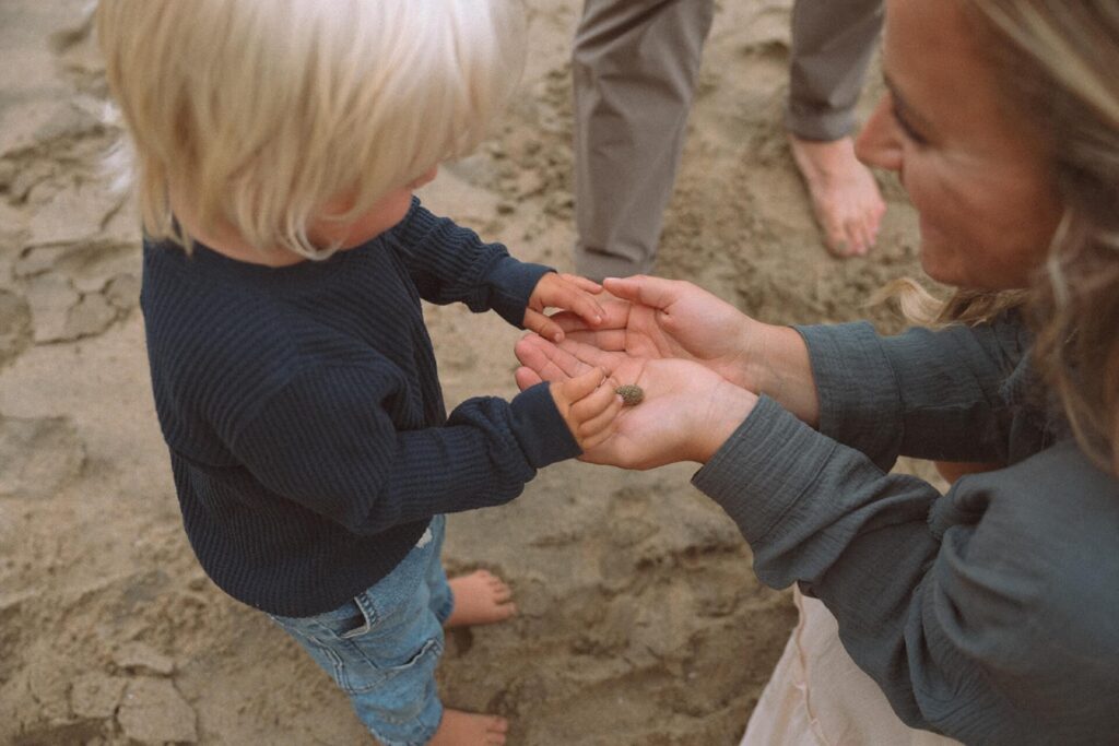 little boy touching crab in mothers hands crescent bay