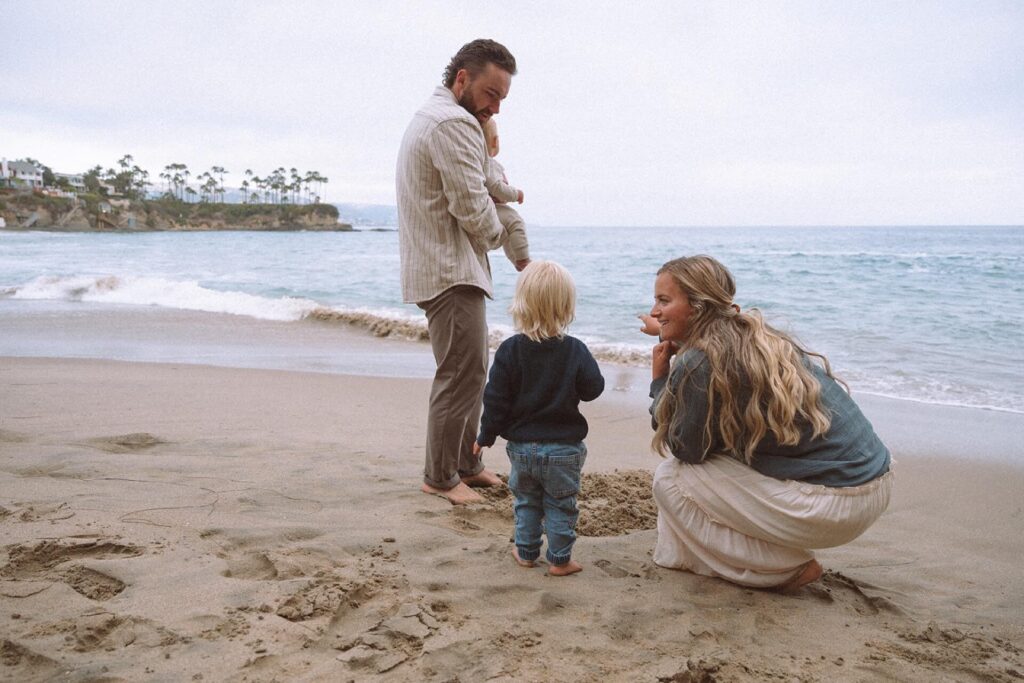 mother pointing at ocean with little boy and family