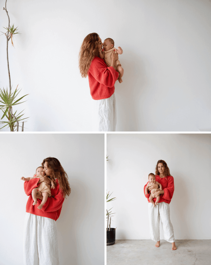 mother wearing red sweater holding baby in yellow oneside for family photos