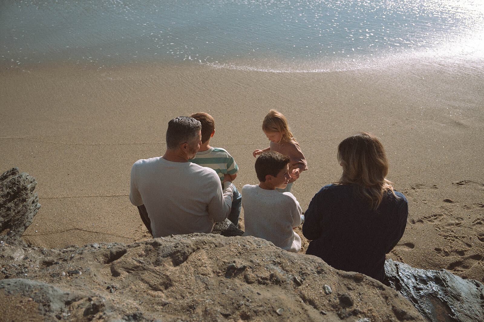 family of five sitting on rock at laguna beach