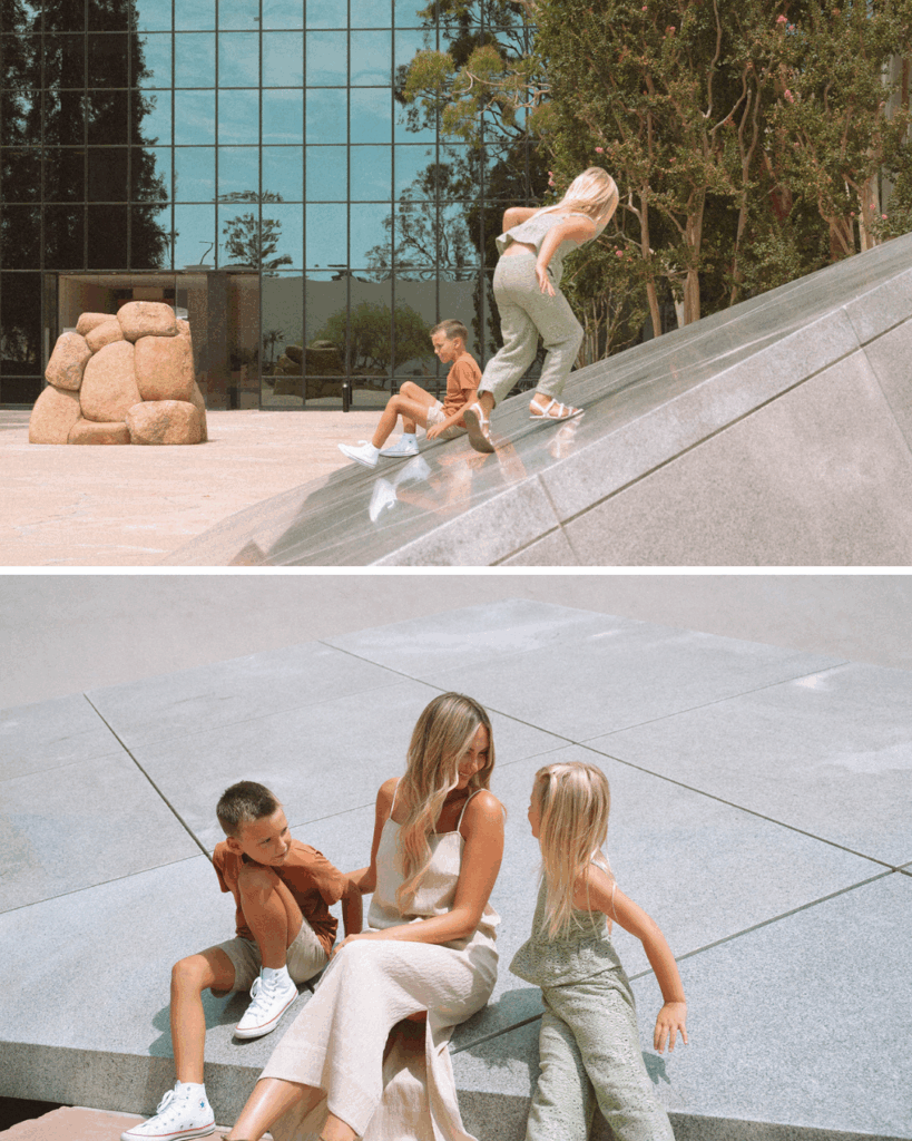 Mother and children climbing and sitting on the geometric stone sculpture in Costa Mesa.
