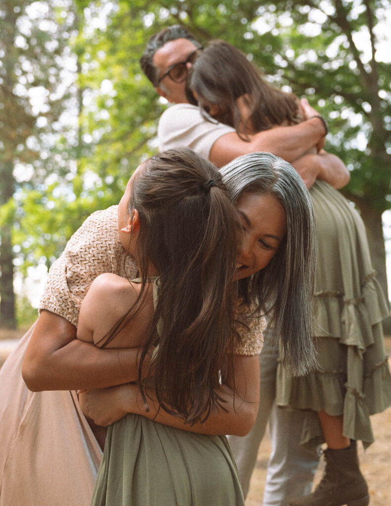 Parents hugging their daughters in the trees during a fall family photography session in Orange County.