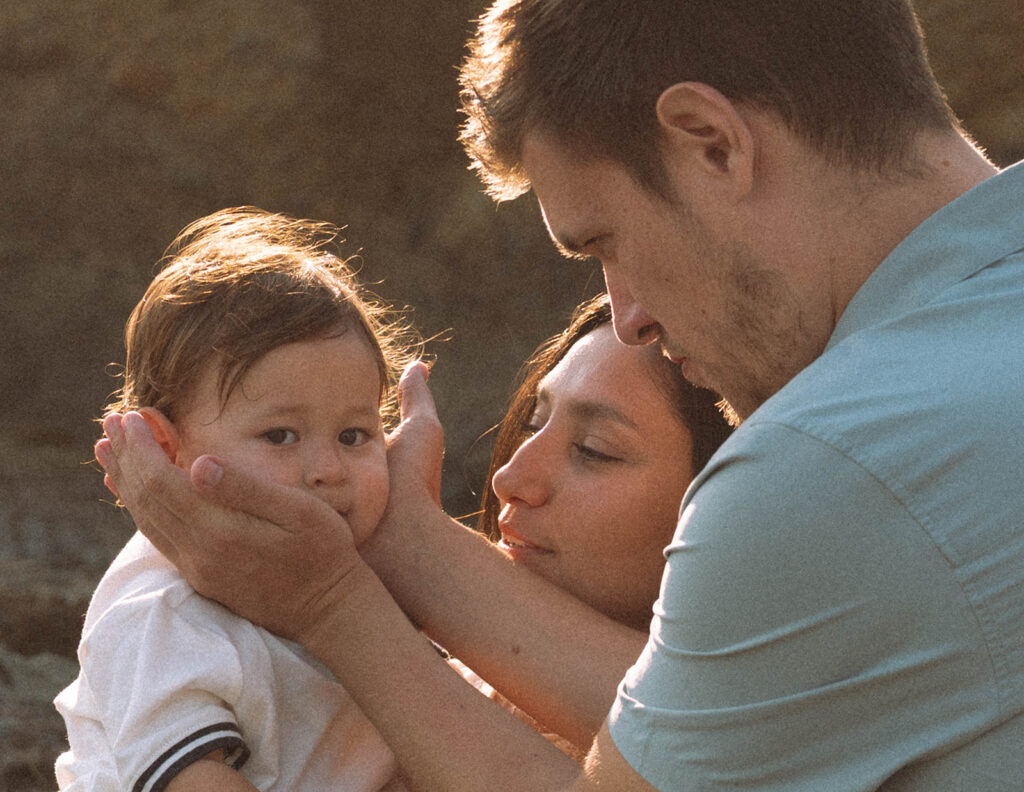 Parents cuddling their baby during a sunset family photography session at Shaw's Cove
