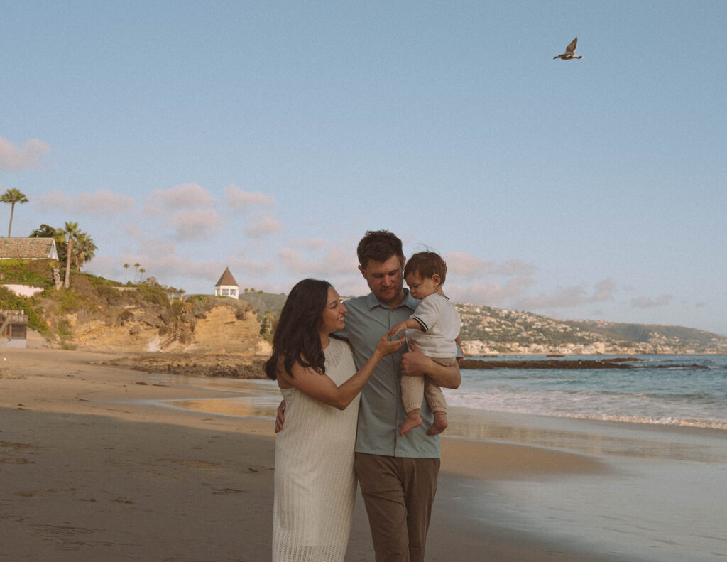 Family walking barefoot along the sand during sunset at Laguna Beach.
