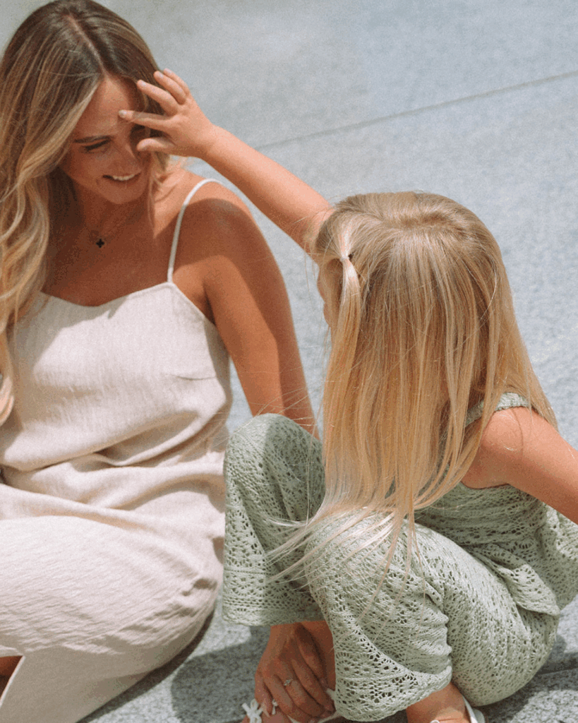 Mother smiling as her daughter brushes hair from her face during a playful family session at Noguchi Garden in Costa Mesa.