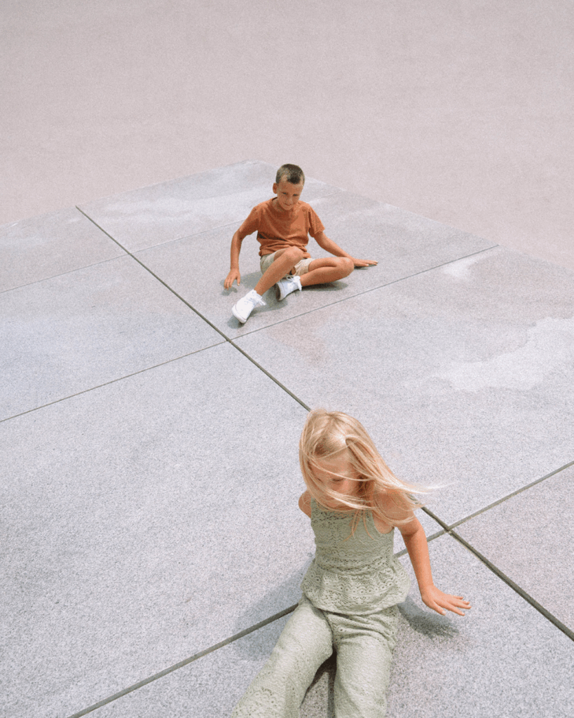 Two children sitting on the concrete platforms at Noguchi Garden in Costa Mesa during a family photo session.